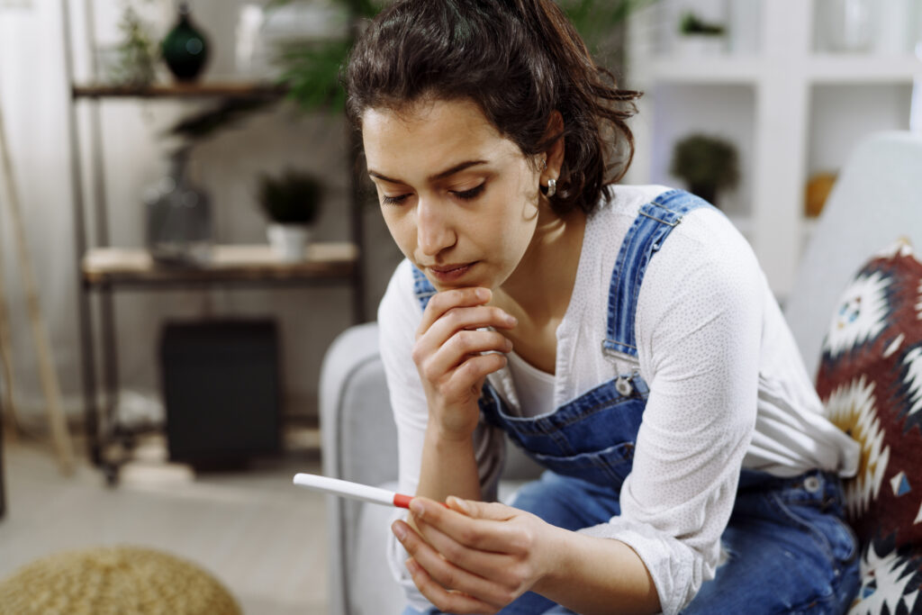 Woman sitting thoughtfully at a table while considering abortion at First Care Women’s Health.