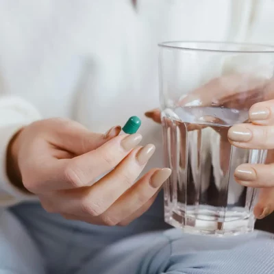 Woman holding a pill and a glass of water