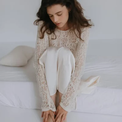 Woman sitting on bed looking down with thoughtful expression